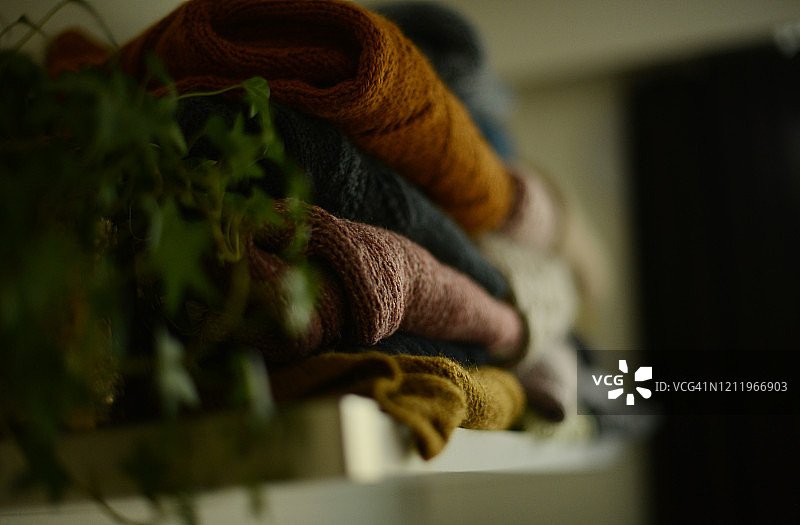 白色架子上靠着盆栽绿植的针织毛衣图片素材