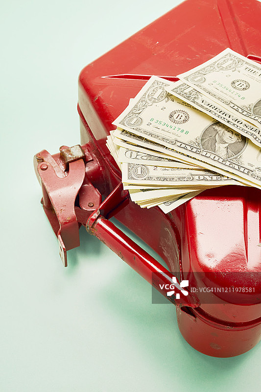 青绿色背景上的红色油桶和美元钞票俯视图图片素材