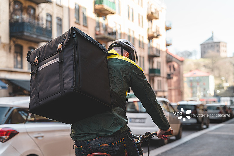 男人在城市里骑自行车送餐图片素材