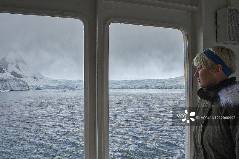 在短暂的夏季，女人欣赏南极洲半岛壮丽的景色图片素材