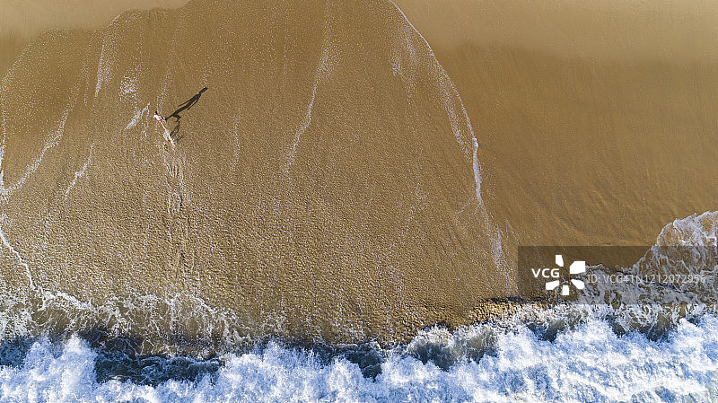 年轻男子站在海滩上的俯视图图片素材
