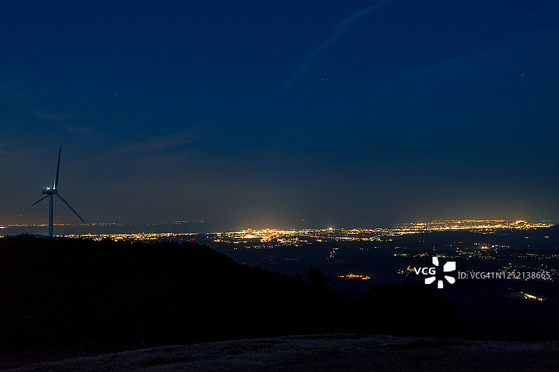 夜景：风力发电机和城市灯光图片素材