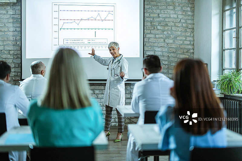 在医院做演示的快乐资深医生图片素材