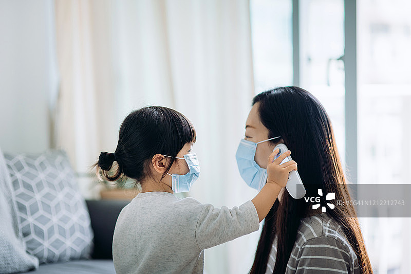 幼儿用电子体温计测量生病母亲的体温图片素材