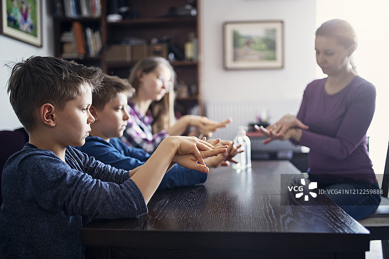 母亲教孩子们用抗菌洗手液清洁双手图片素材