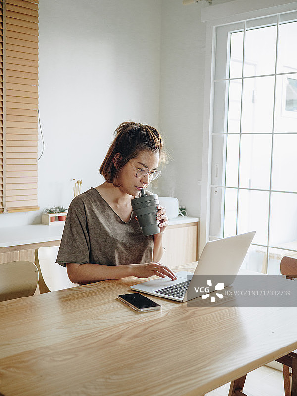 亚洲年轻女性在家放松使用笔记本电脑图片素材