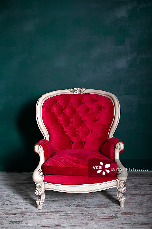 祖母绿色墙壁旁的红色天鹅绒复古扶手椅图片素材
