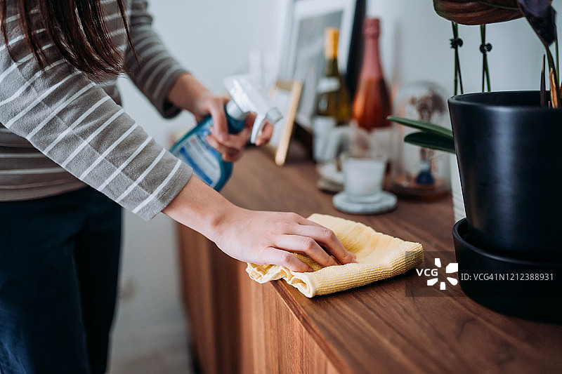 年轻女子在家清洁橱柜表面图片素材
