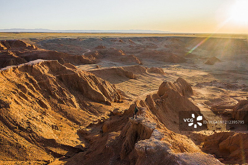 航拍男子在日落时分眺望戈壁沙漠图片素材
