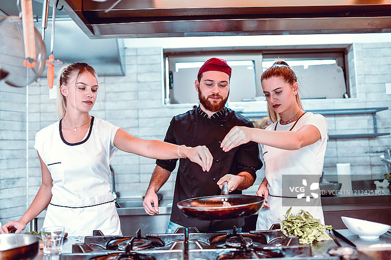 男厨师让女厨师为菜肴调味图片素材