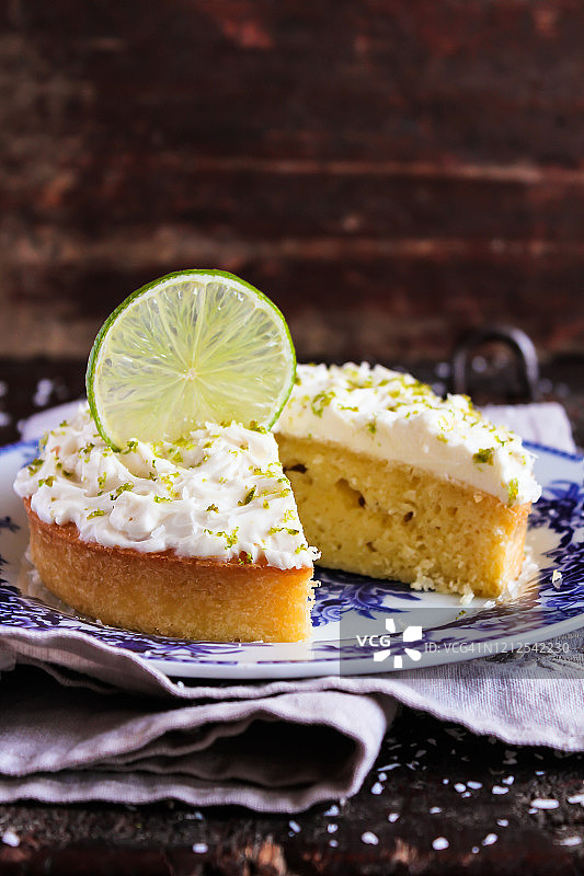自制香草奶油奶酪青柠蛋糕，饰以新鲜青柠片和青柠皮屑图片素材