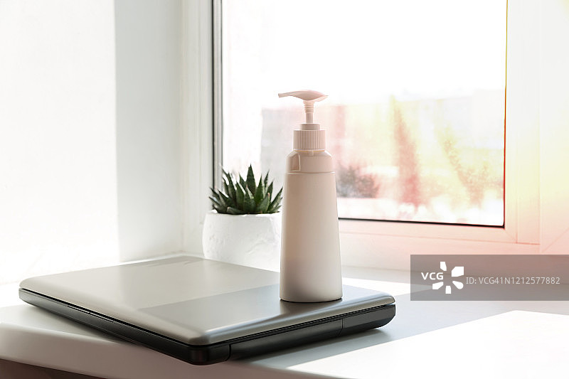 工作场所和笔记本电脑上的免洗洗手液。个人卫生概念，手部消毒，病毒防护，疫情期间的远程工作图片素材