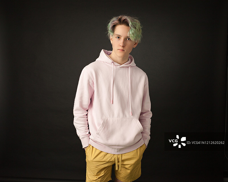 黑色背景下留着绿色头发的青少年男孩影棚肖像图片素材