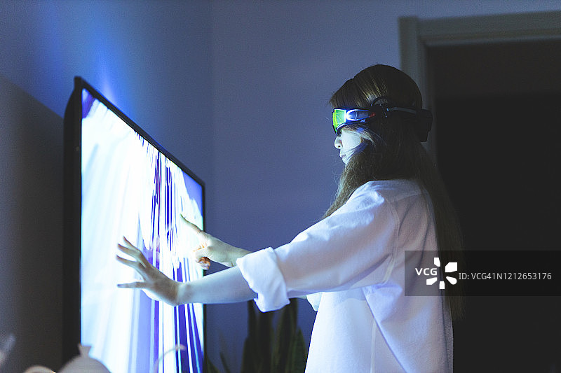 戴增强现实眼镜，用手触摸屏幕的年轻女子图片素材