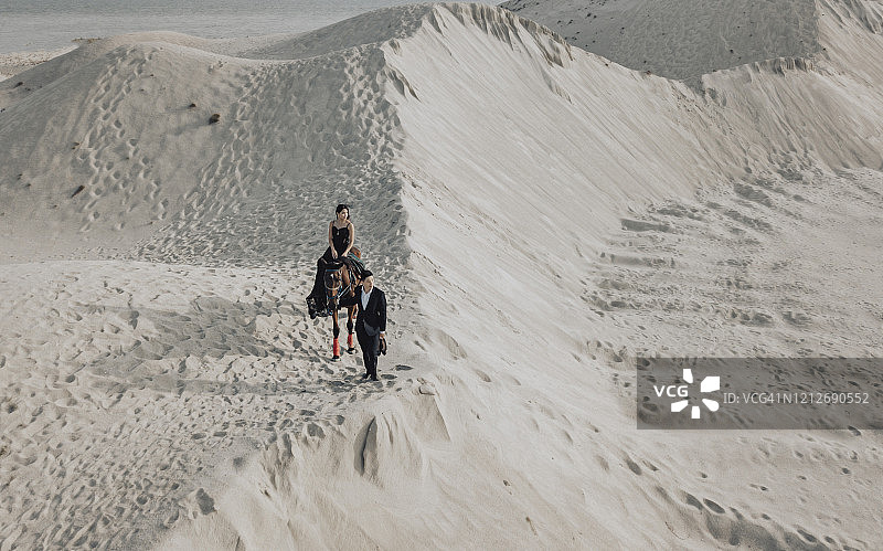 黄昏时分在马六甲沙漠沙丘骑马的亚洲情侣图片素材