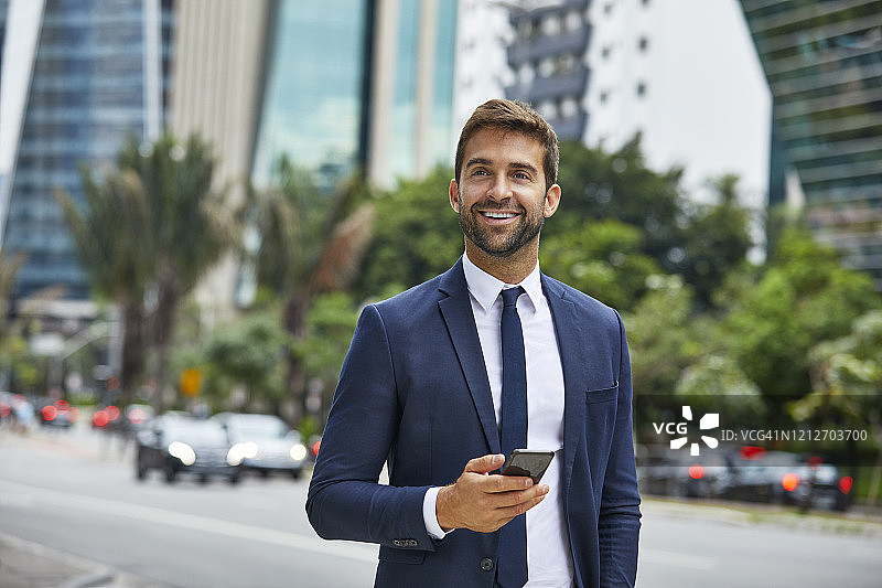 在城市里拿着手机看向远方的商人图片素材