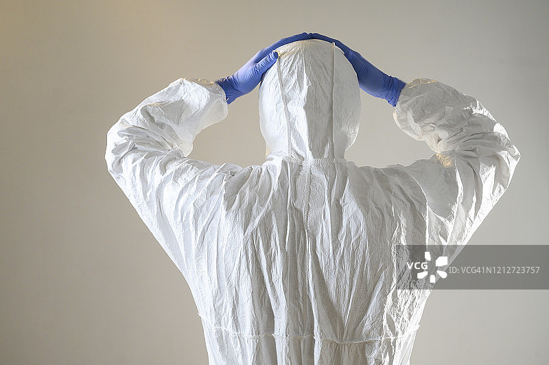 坏消息。戴着手套和防护服的男人举起双手，关于冠状病毒和其他病毒的概念。图片素材