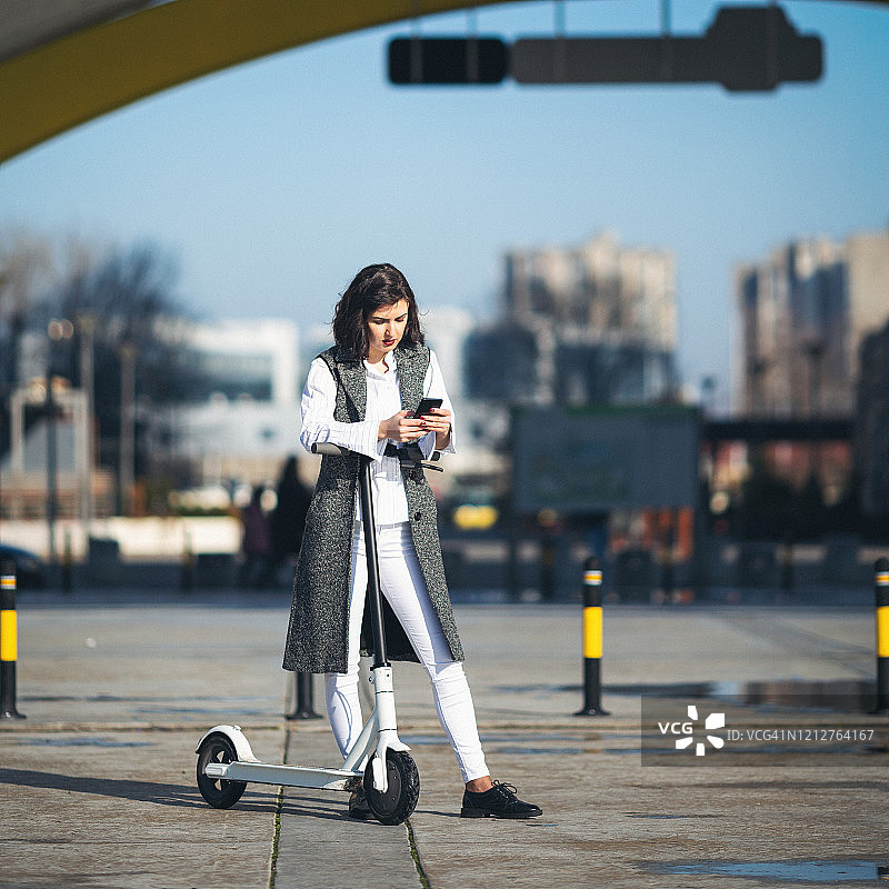 女商人骑电动滑板车在城市中图片素材