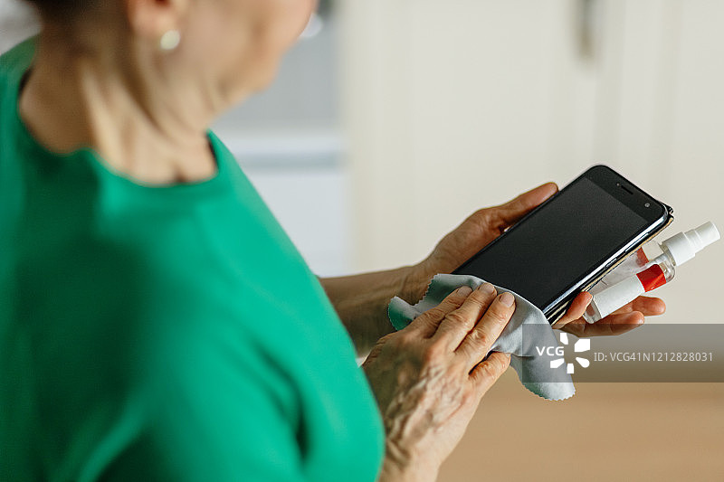 中年妇女用消毒剂清洁手机图片素材