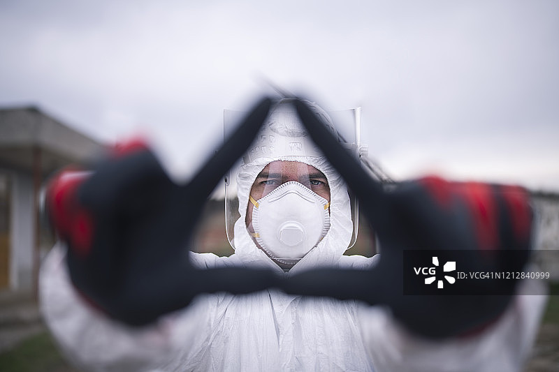 身穿防护服，用手做出危险标志的男人图片素材