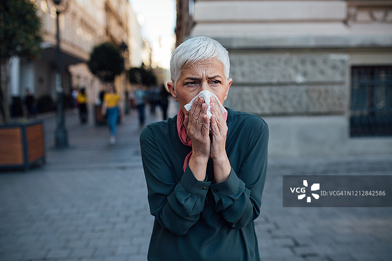 用手帕捂嘴咳嗽的年长女人图片素材