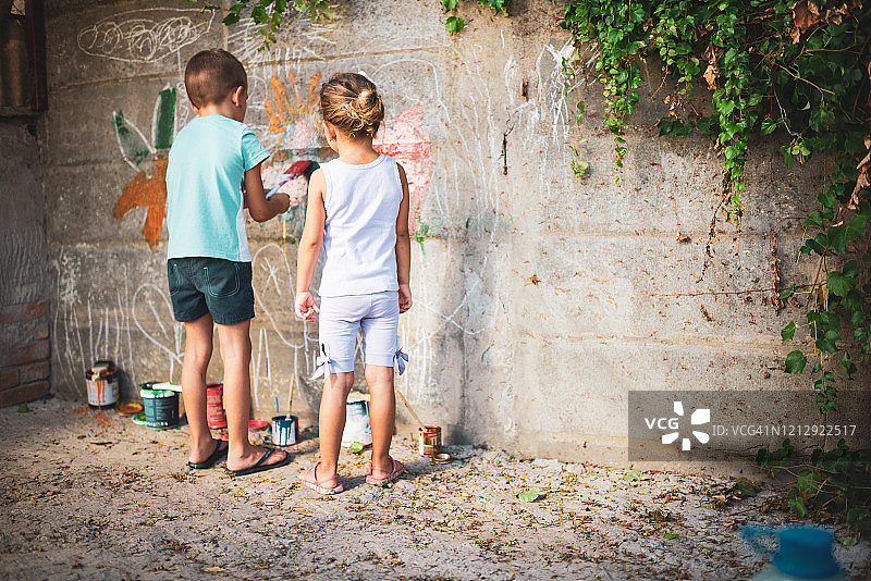 快乐的小朋友们在墙上绘画，玩得很开心图片素材