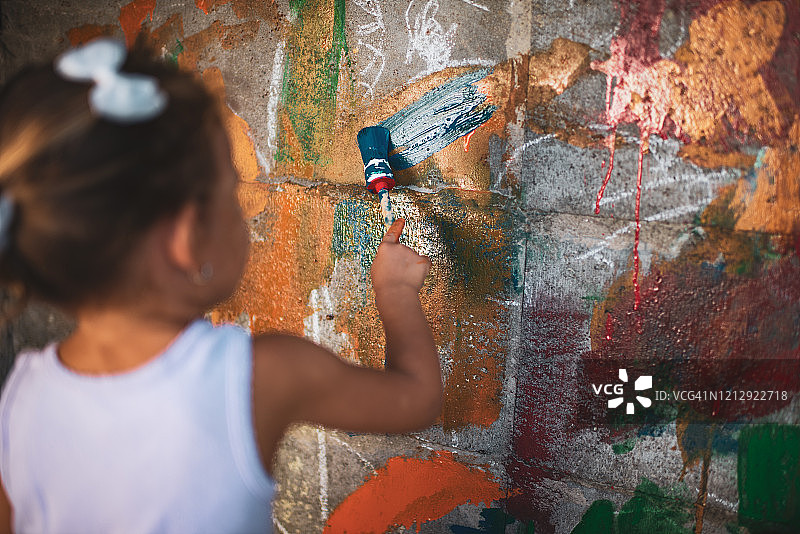 快乐的小女孩开心地在墙上绘画图片素材