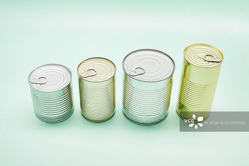 蓝绿色背景中不同尺寸罐头食品升序排列静物图片素材