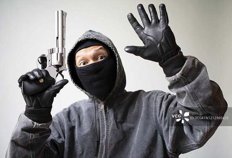 身穿黑色防护服的抢劫犯，举起双手特写图片素材