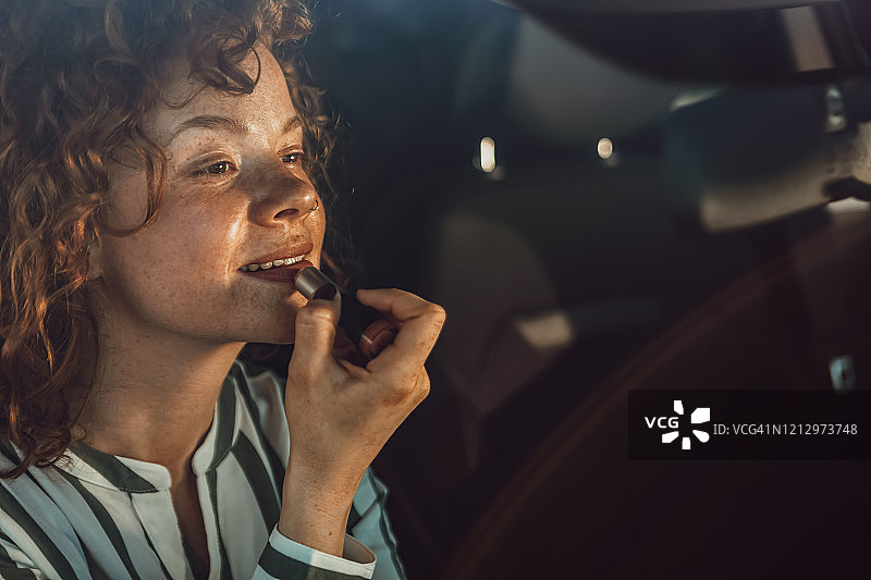 快乐的年轻女孩在交通堵塞时涂口红图片素材