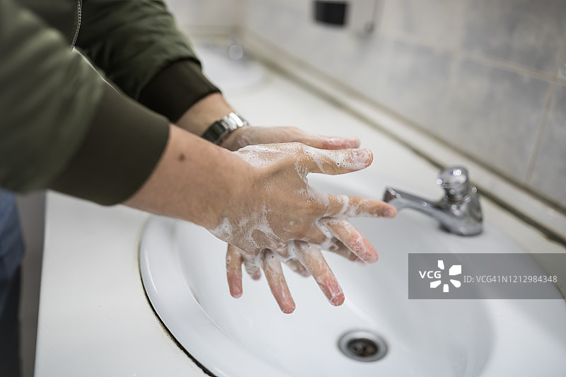 戴口罩的男人在公共卫生间洗手图片素材