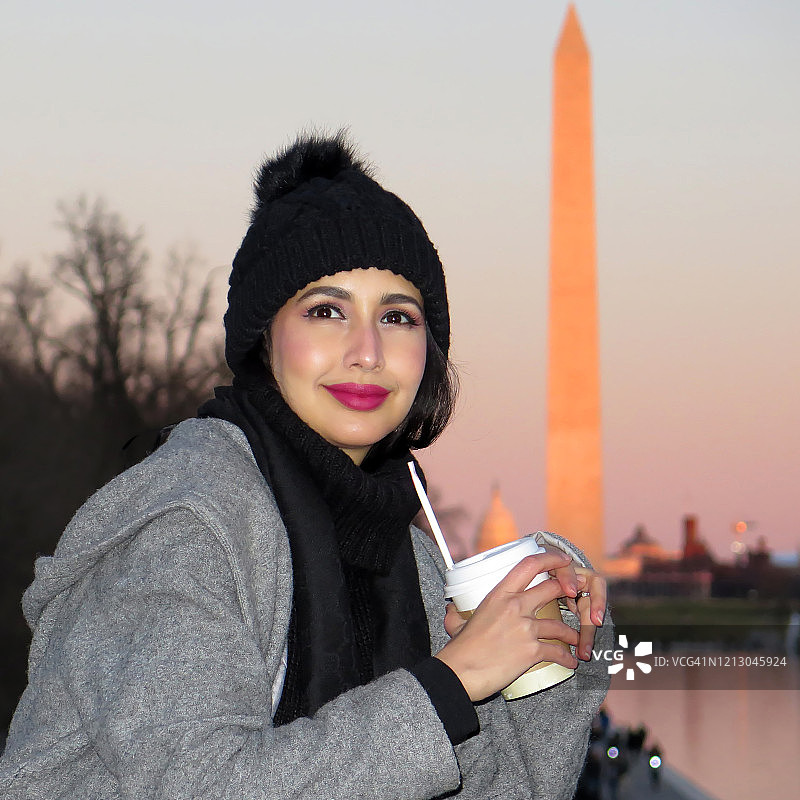 年轻女游客在日落时的华盛顿纪念碑旁图片素材