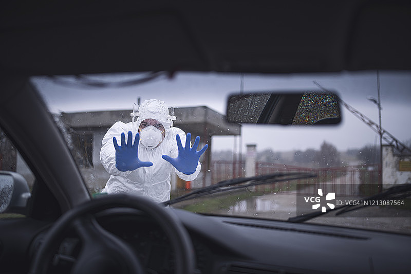 穿着防护服控制边境交通的男人，关闭边境病毒大流行图片素材