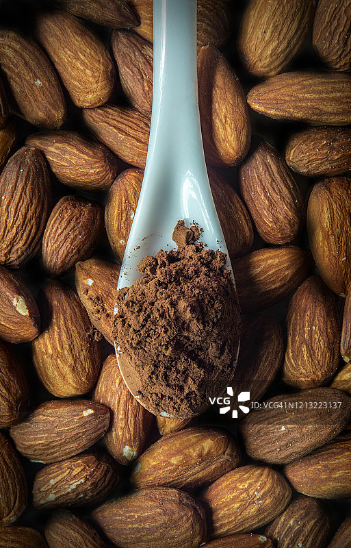 杏仁背景上的勺子可可粉图片素材