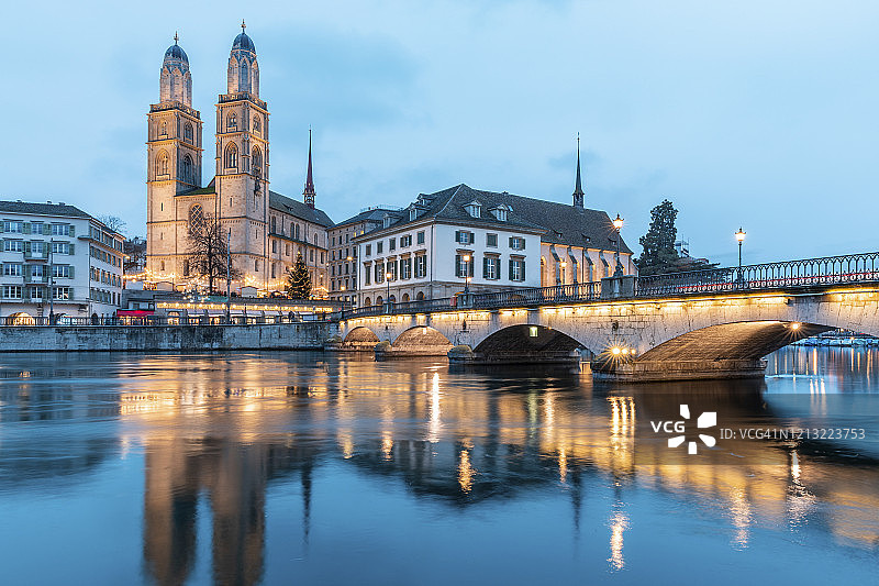 瑞士苏黎世黄昏时分的格罗斯大教堂与利马特河上的明斯特桥图片素材