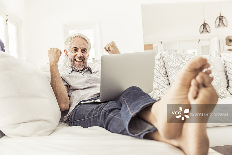 在家用笔记本电脑欢呼的成熟男人图片素材