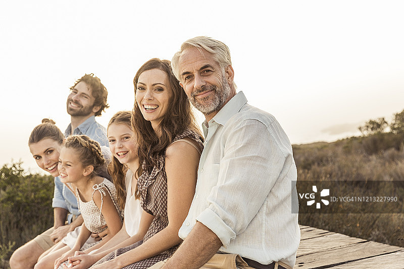 大型家庭坐在木板路上欣赏日落图片素材