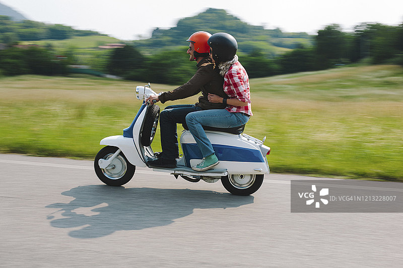情侣骑着复古摩托车在意大利托斯卡纳的乡村道路上图片素材