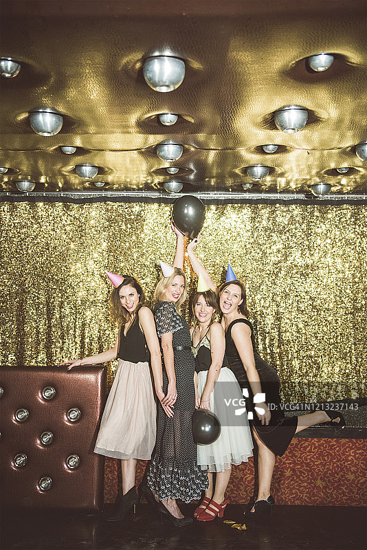 四个戴着派对帽的快乐女人在俱乐部里图片素材