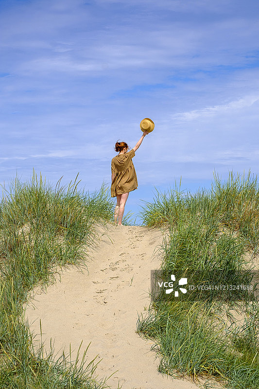 戴着帽子站在瑞典斯科讷法尔胡特海滩沙丘上的少女图片素材
