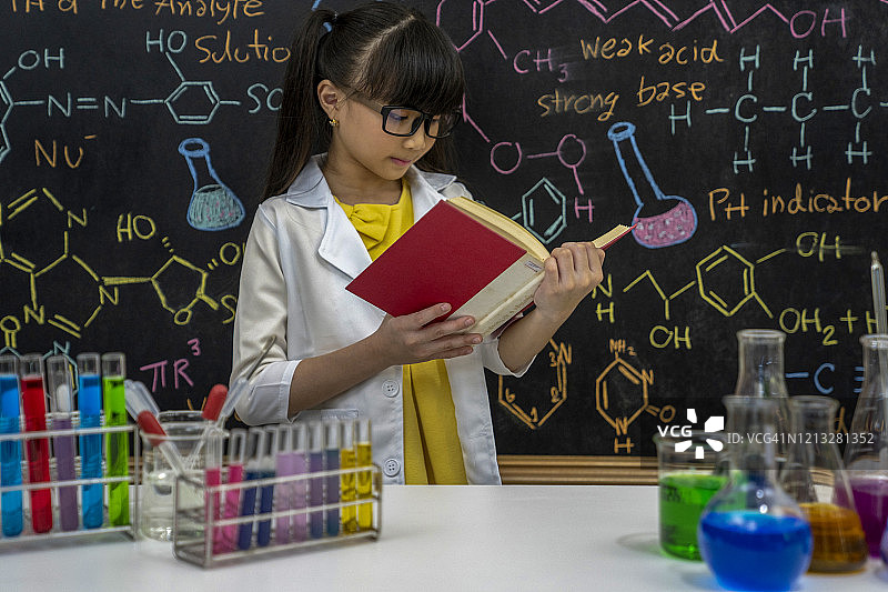 可爱的小学女生玩着试管和彩色液体。学校化学实验。学校教育。图片素材