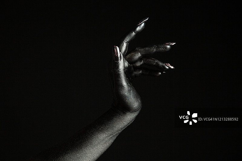 涂成黑色的女人手，带有黑色美甲，像是怪物身体的一部分图片素材