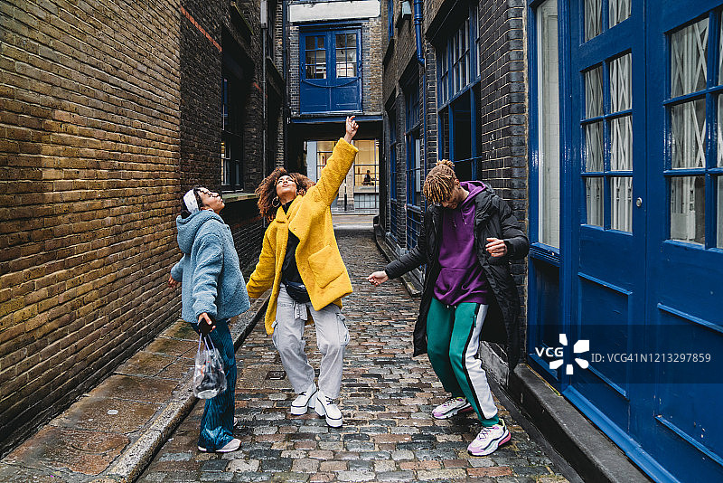 三个快乐的朋友在城市里一起跳舞图片素材