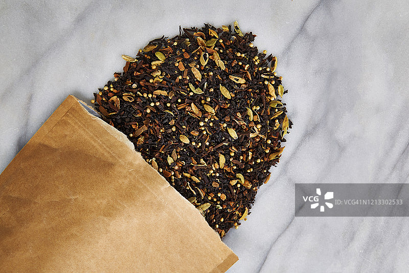 棕色纸袋中的散装茶叶洒落在云石背景上的俯视照片图片素材
