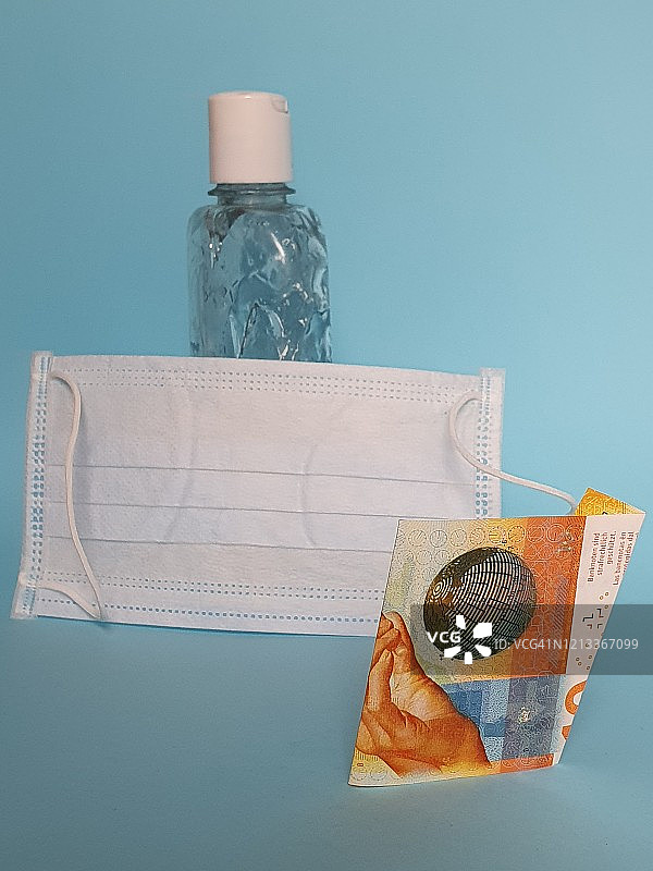 瑞士法郎纸币、口罩和酒精凝胶瓶，蓝色背景图片素材