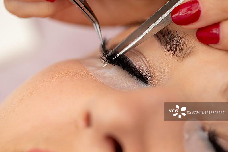 美容师用镊子将假睫毛精确地贴在睫毛线上图片素材