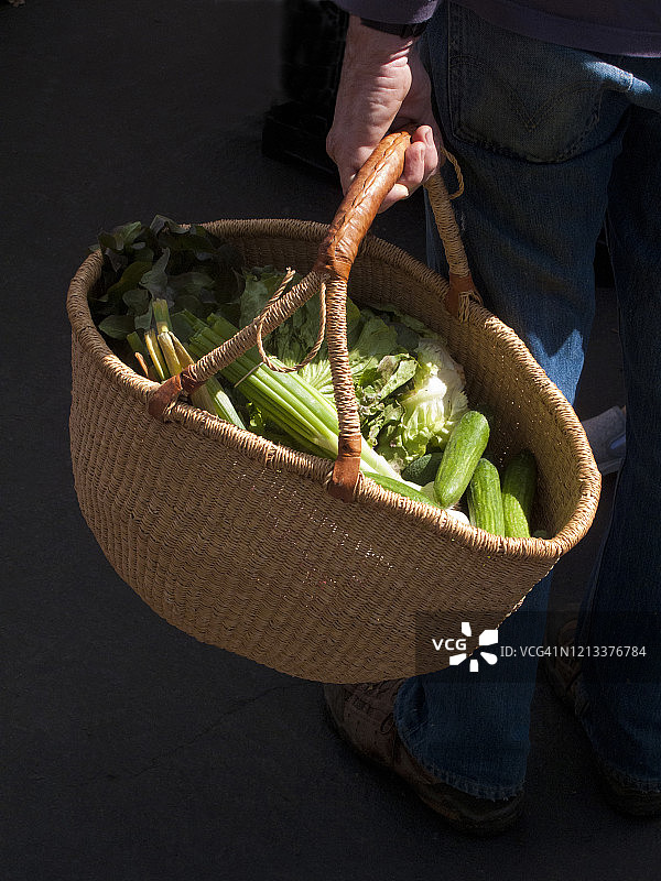 男人在农贸市场手提蔬菜篮购物图片素材