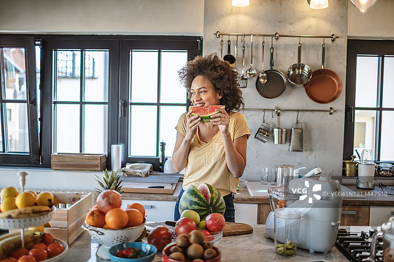 女人在厨房享用新鲜西瓜图片素材