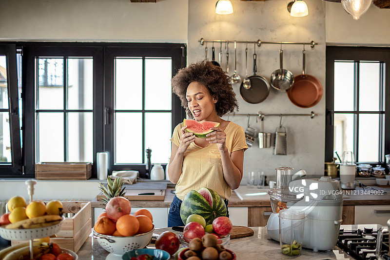 女人在厨房享用新鲜西瓜图片素材