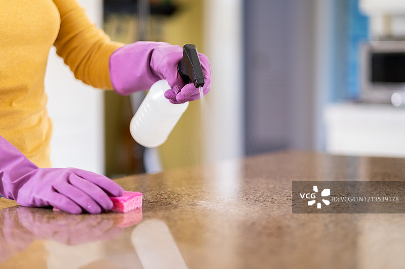 女人用消毒剂和海绵擦拭台面图片素材